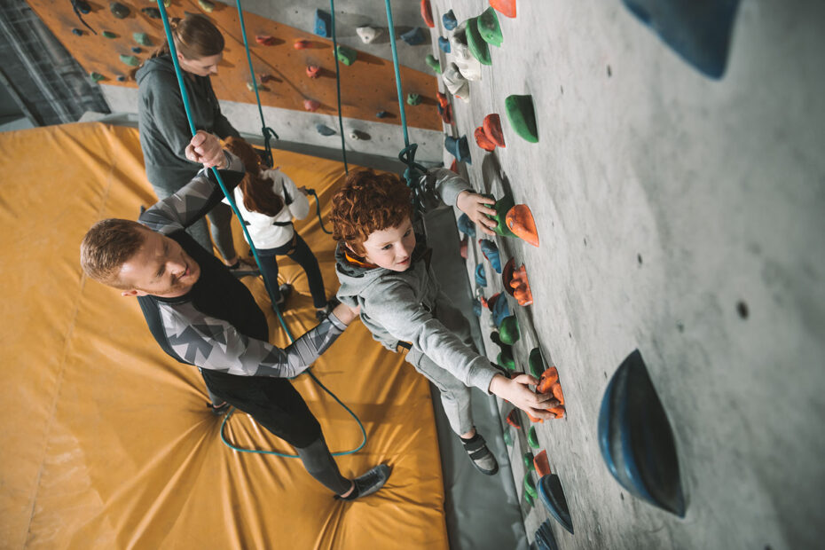 Little boy climbing indoor rock wall