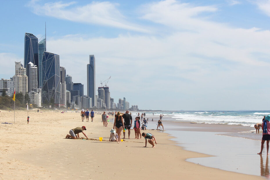 People playing on the beach with the Surfers Paradise skyline in the background.